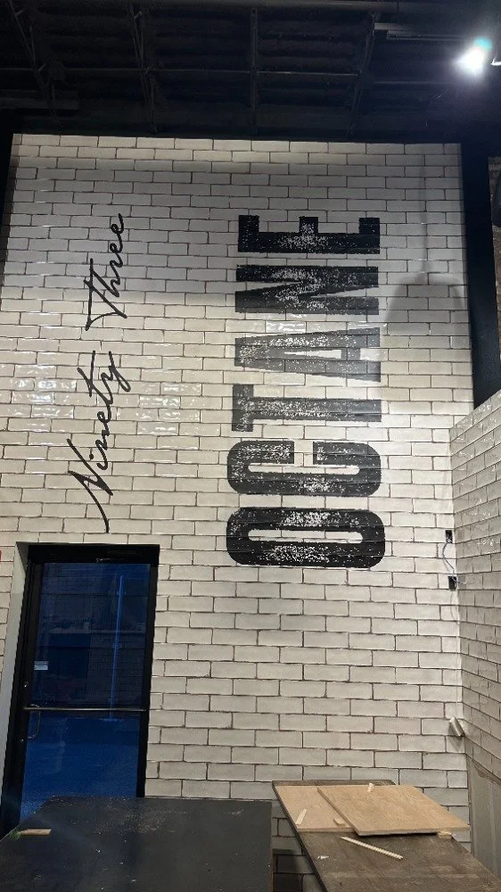 Ninety Three Octane lettering printed onto a white tile brewery wall